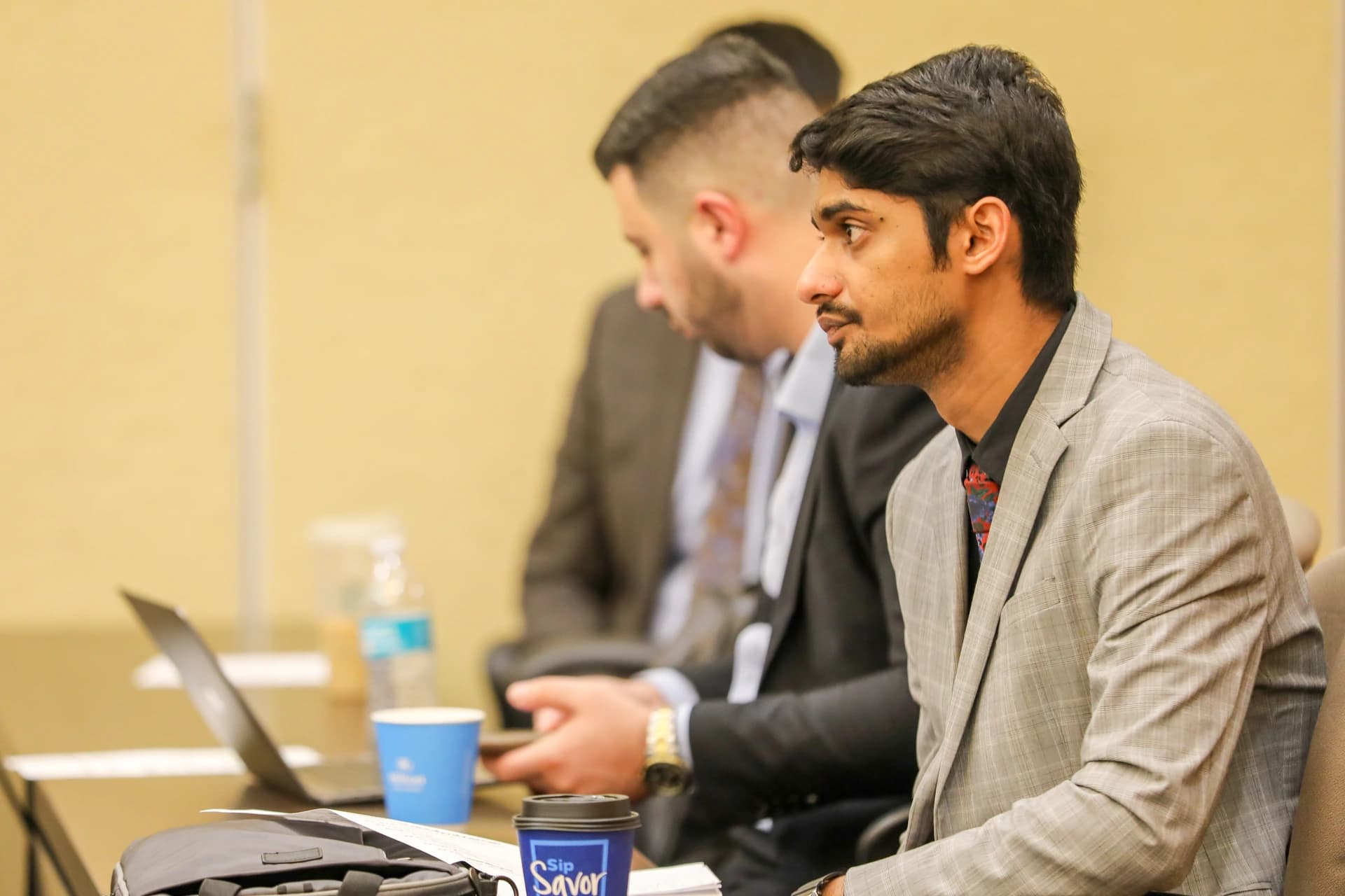 A participant listening attentively during a workshop, with colleagues seated beside him.