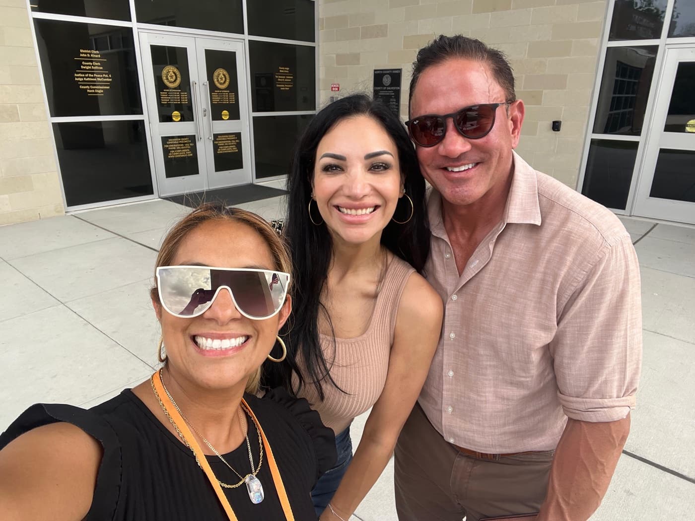 A fundraiser and two supporters smiling outside a county building