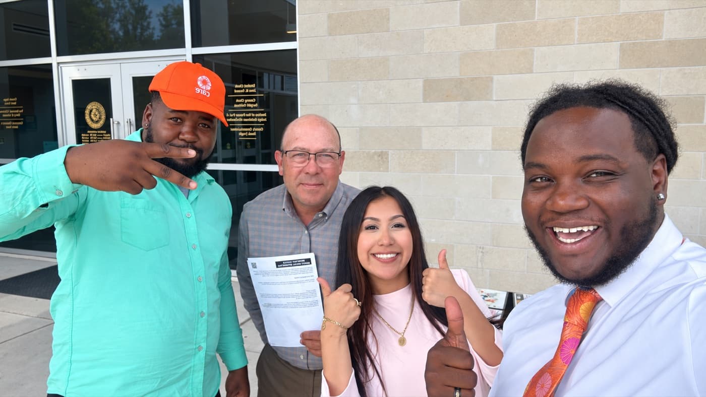 Two fundraisers and two supporters with a signed form outside a county building