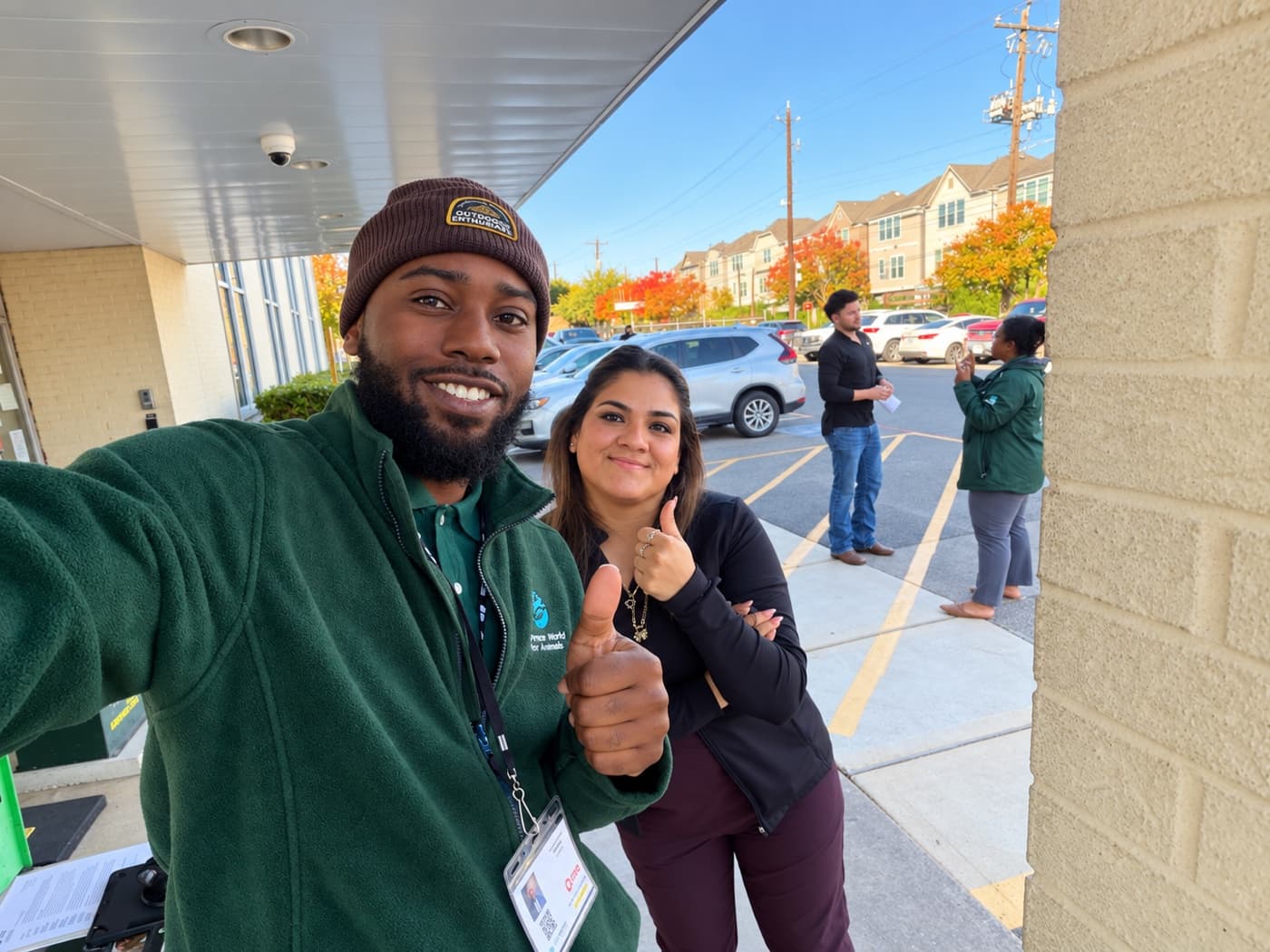 A fundraiser in a beanie and a supporter giving thumbs up outside an office entrance