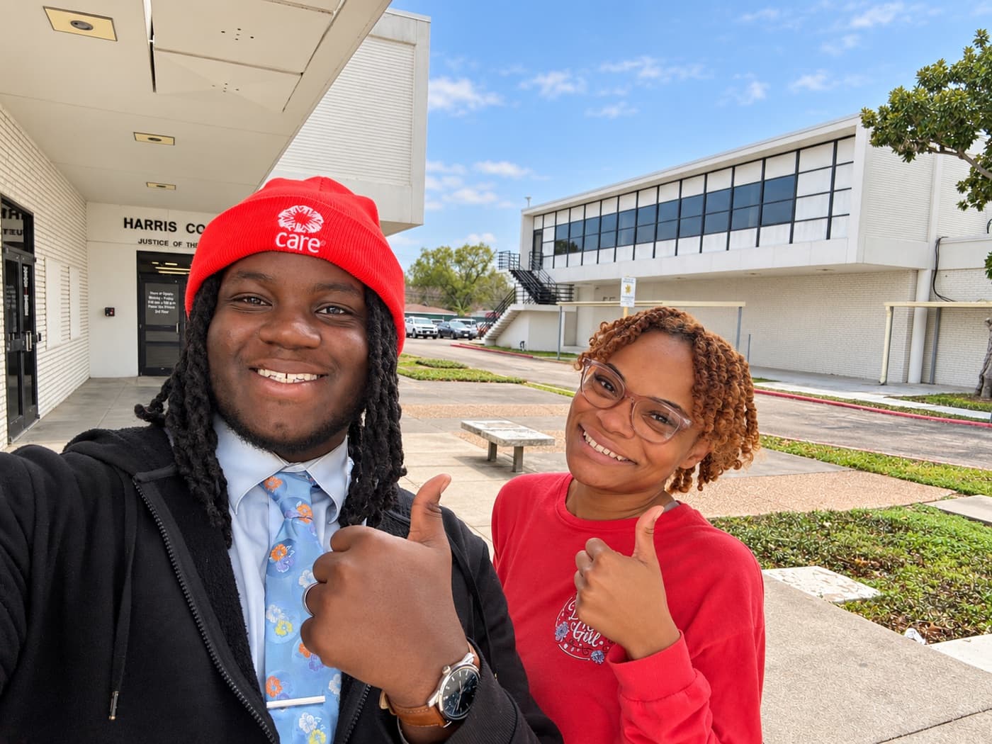 A fundraiser and a supporter giving thumbs up outside a county courthouse