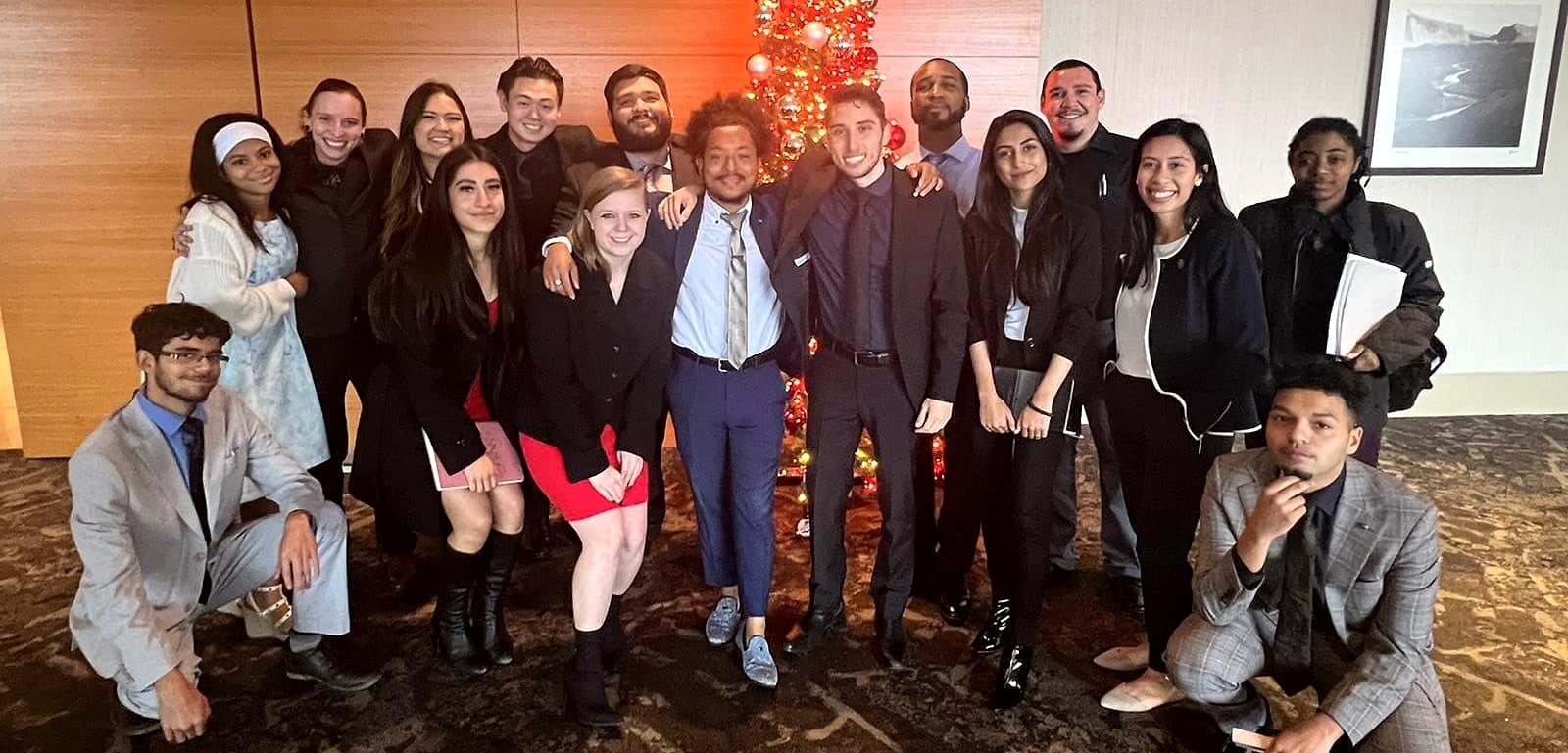 Zach Pyron with his San Antonio team, about seventeen people in business dress, posed around a lit holiday tree.