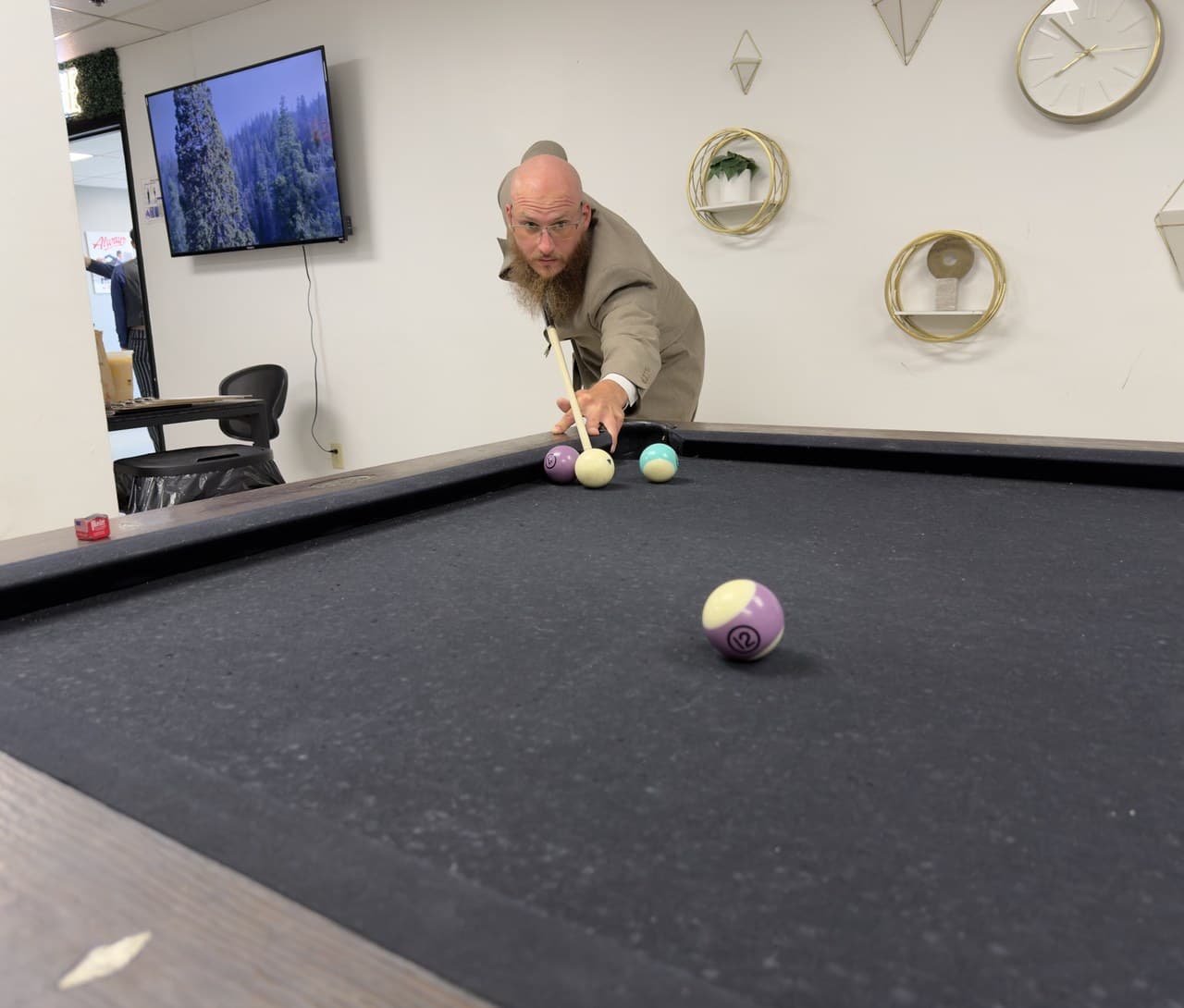 A team member lining up a shot at the pool table in the office.