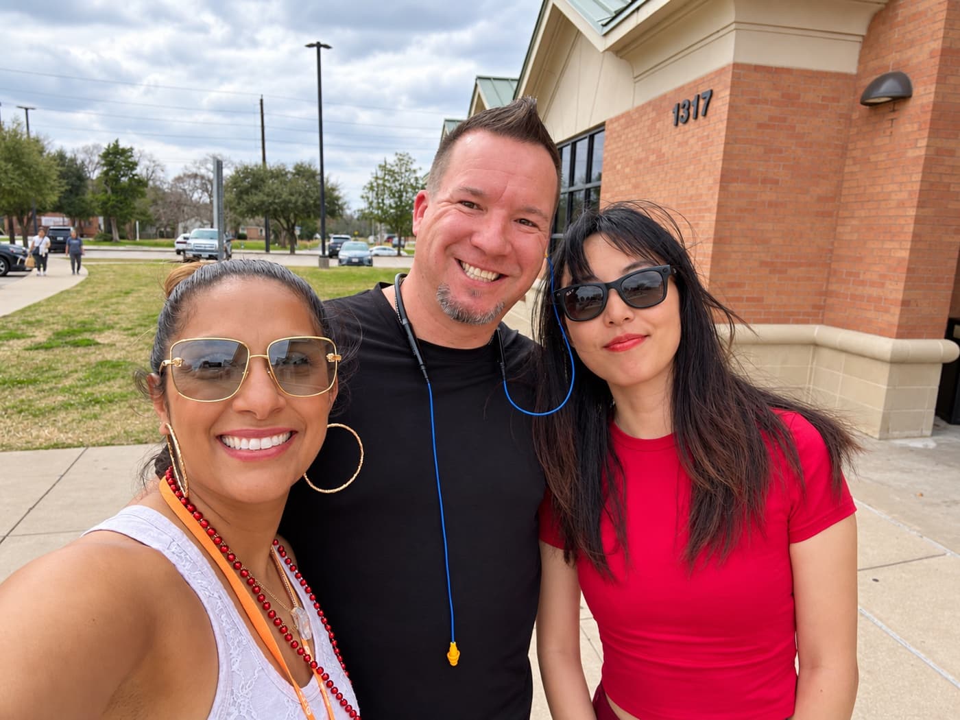 A fundraiser and two supporters smiling outside a brick civic building
