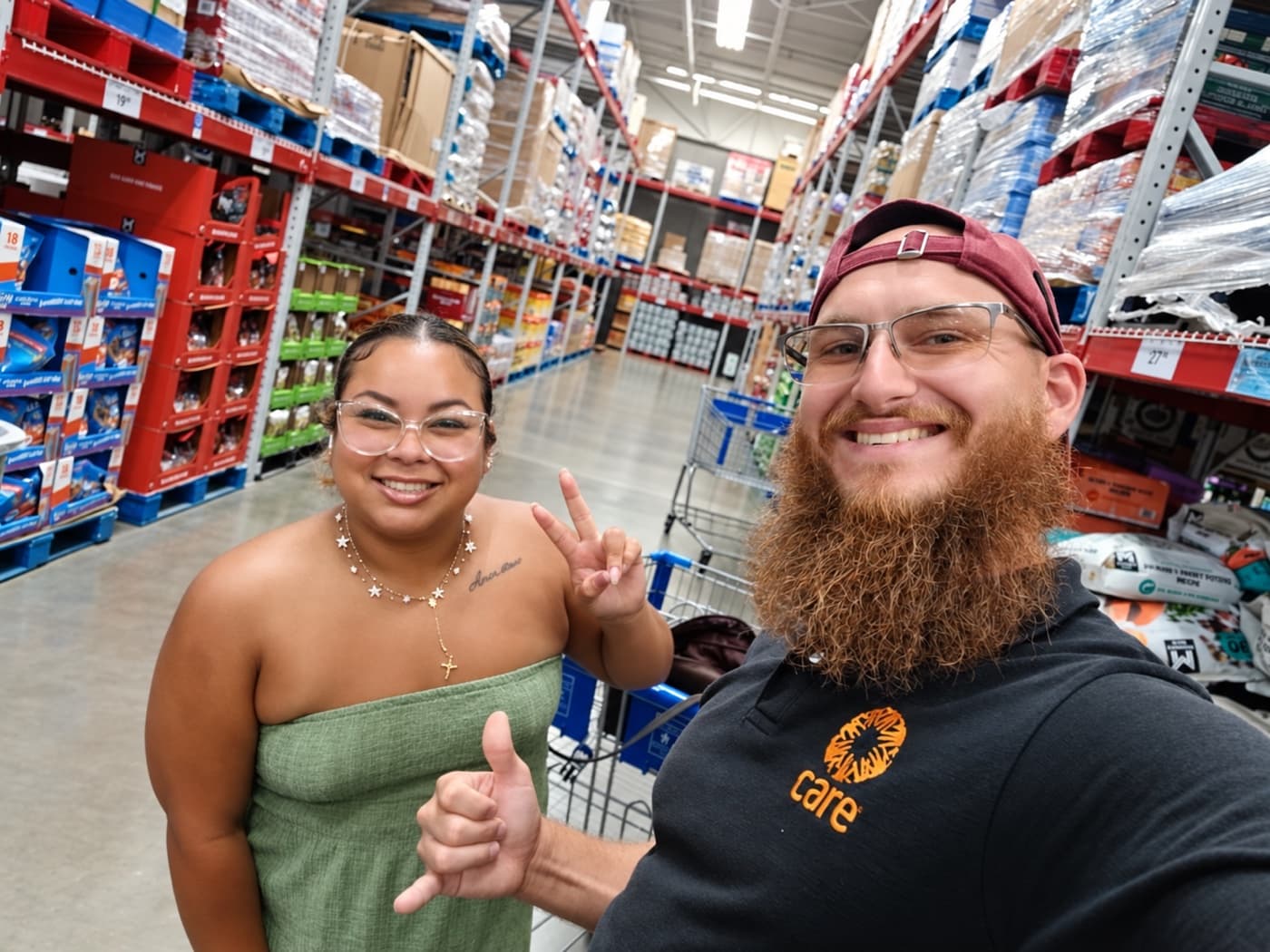A fundraiser and a supporter flashing peace signs in a warehouse store aisle