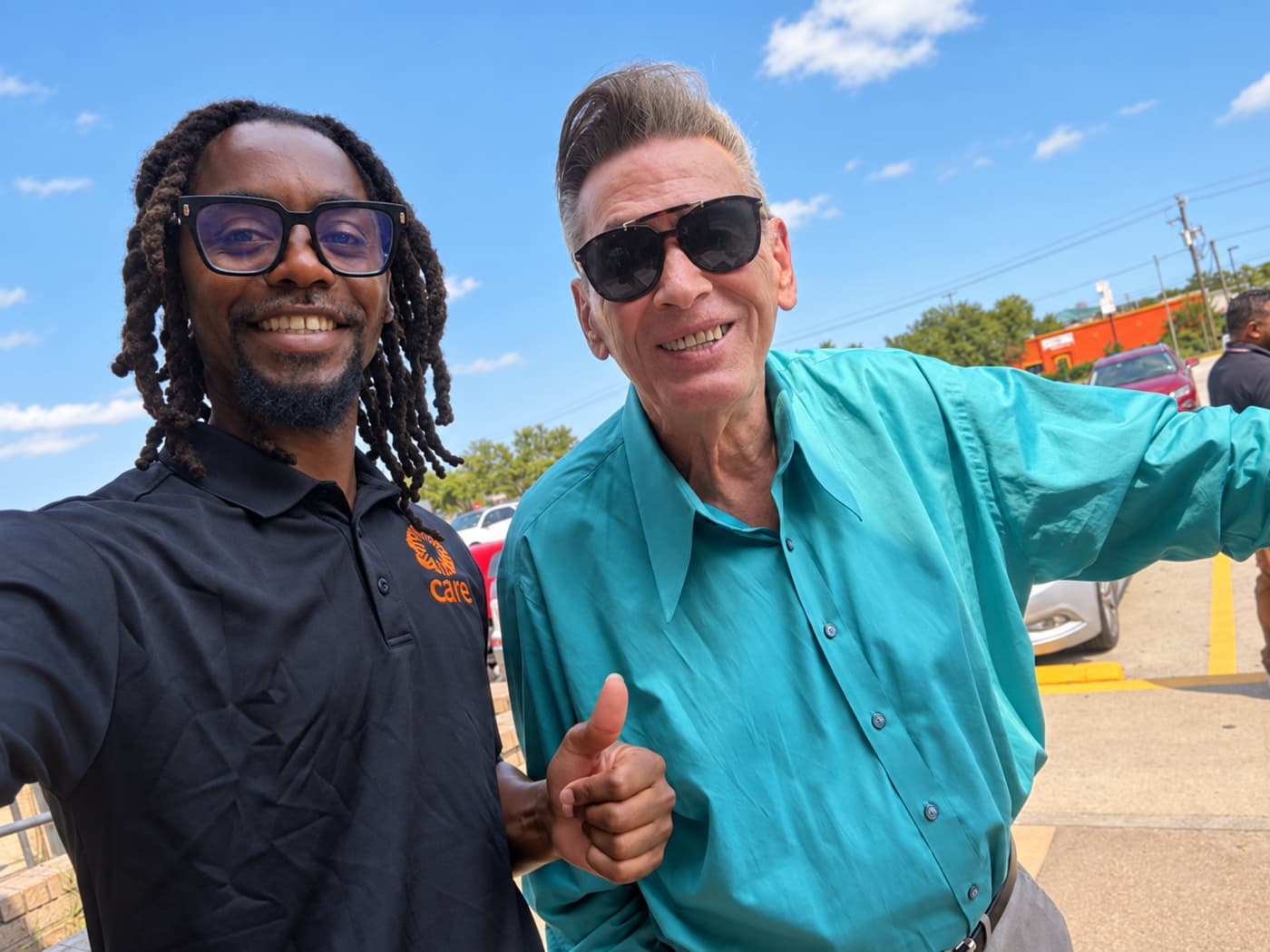 A fundraiser and a supporter giving a thumbs up in a sunny parking lot