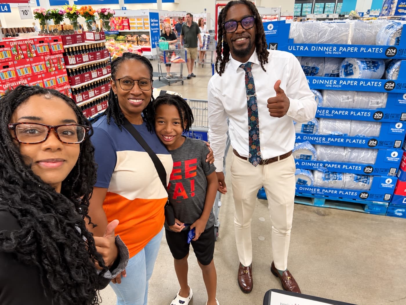 A fundraiser and a family of three giving thumbs up in a warehouse store