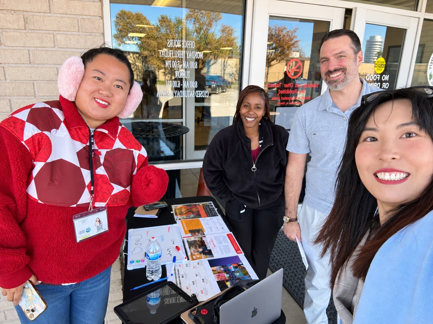 A fundraiser and three supporters around a sign-up table outside an office entrance