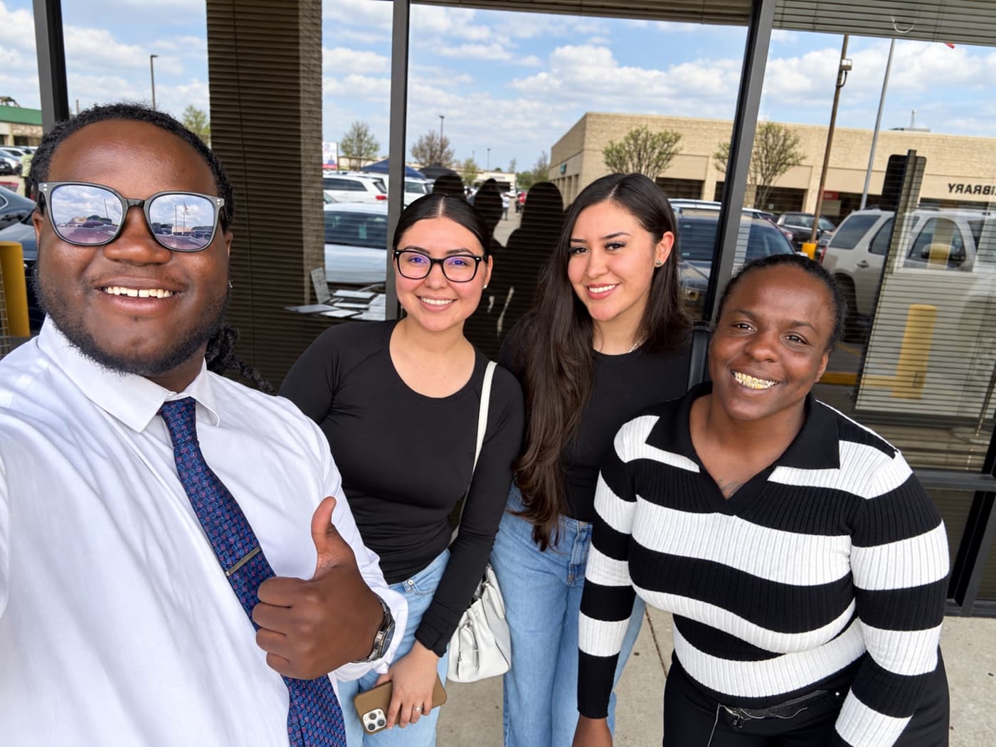 A fundraiser and three supporters smiling outside a storefront