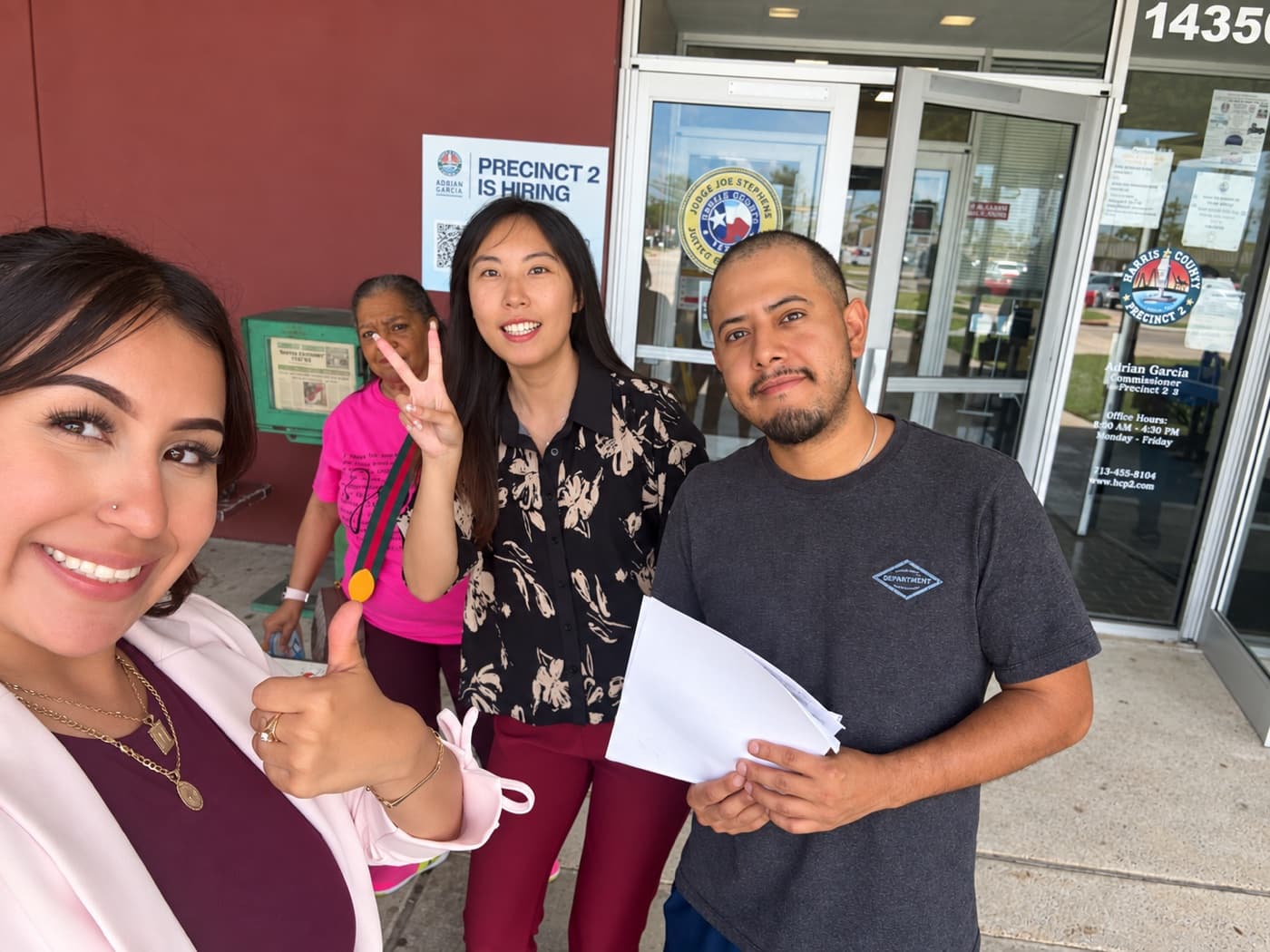 A fundraiser and two supporters outside a county office, one holding a signed form