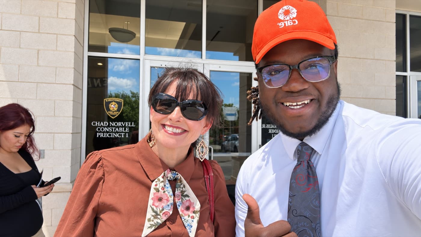 A fundraiser in a cap and a supporter smiling outside a government office